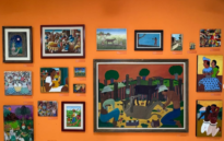 Parede laranja com quadros de artistas que estão exposto na sala permanente do museu, destaque para as cores vibrantes das obras.