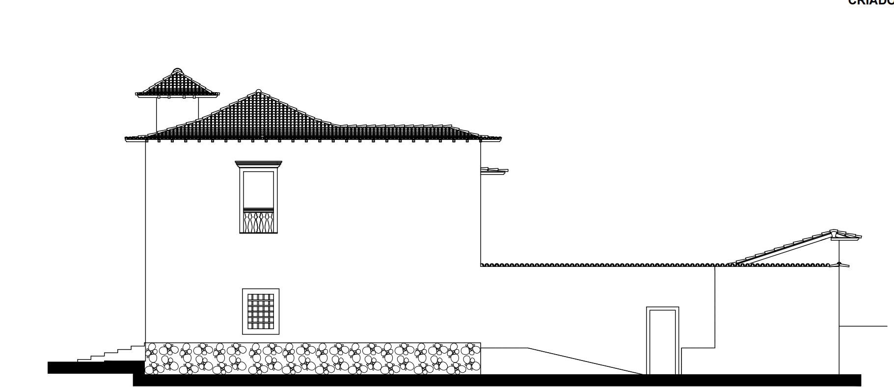 Desenho técnico da fachada lateral do Museu das Bandeiras. A edificação apresenta dois pavimentos com cobertura em telhado de duas águas, beirais salientes e uma mansarda no canto esquerdo. Há uma janela no pavimento superior com guarda-corpo e uma janela com grade no pavimento inferior. A base da construção possui embasamento em pedra. À direita, está o muro com uma porta de acesso.