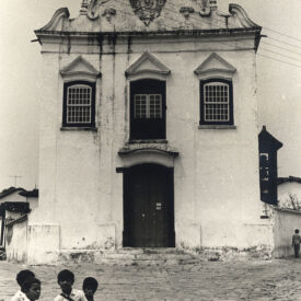 A fachada do Museu está retratada em preto e branco. A porta principal fica ao centro da fachada, encimada por janela central no pavimento superior, com duas janelas ao lado, as três decoradas com cornijas em formato triangular, lembrando pequenos frontões. Completando a composição, no topo da fachada, o frontão ondulado com brasão e cruz.
