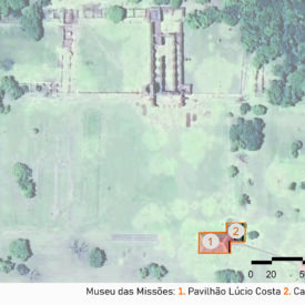 Imagem aérea do museu, com dois grupos destacados por contorno laranja. No canto inferior direito da imagem, está indicado o número 1, referente ao Pavilhão Lúcio Costa, e o número 2, referente à Casa do Zelador. Mais ao centro da imagem, é possível observar as ruínas, remanescentes históricos e arquitetônicos dos antigos povoados missionais, localizadas em uma área gramada e rodeadas por árvores. A imagem inclui a legenda com a identificação das edificações, no canto inferior direito a escala gráfica e, na parte superior esquerda, uma seta indicando o ponto cardeal norte.