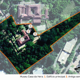 Imagem aérea do museu, com destaque para as principais áreas e limites do terreno. A área total do museu está contornada em laranja, abrangendo uma grande porção arborizada. No centro da imagem está o edifício principal (1), cercado por jardins. À direita, está assinalada a antiga senzala (2), e ao redor, os anexos (3). A imagem também mostra o entorno urbano com ruas, construções vizinhas e vegetação densa. A imagem inclui a legenda com a identificação das edificações, no canto inferior direito a escala gráfica e, na parte superior esquerda, uma seta indicando o ponto cardeal norte.
