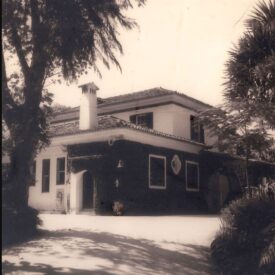 Fotografia antiga do museu, em preto e branco. O edifício tem dois andares, sendo que o andar superior é menor que o térreo. A cobertura é em telhas cerâmicas com quatro águas. No andar térreo, à esquerda, há uma porta em arco, e ao longo da fachada estão dispostas diversas janelas retangulares. Uma parte da parede térrea está revestida por trepadeiras. Árvores e vegetação cercam o edifício, criando sombras no chão à sua frente.