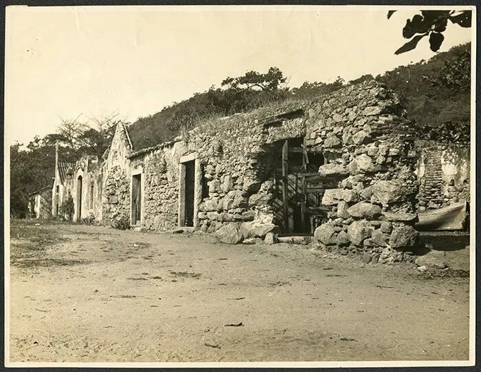 Fotografia histórica do Museu, em tons de sépia. Observam-se os muros da fachada em pedra e as aberturas ao longo de sua estrutura. Nota-se que os muros estão em processo ruim de conservação, com parte deles arruinada, à direita da fotografia.