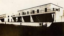 Fotografia histórica em preto e branco do museu, na sua origem de edificação residencial. O edifício possui dois andares com fachada em linhas retas, janelas retangulares no segundo andar e aberturas no térreo. Uma varanda com parapeito contínuo percorre o pavimento superior.
