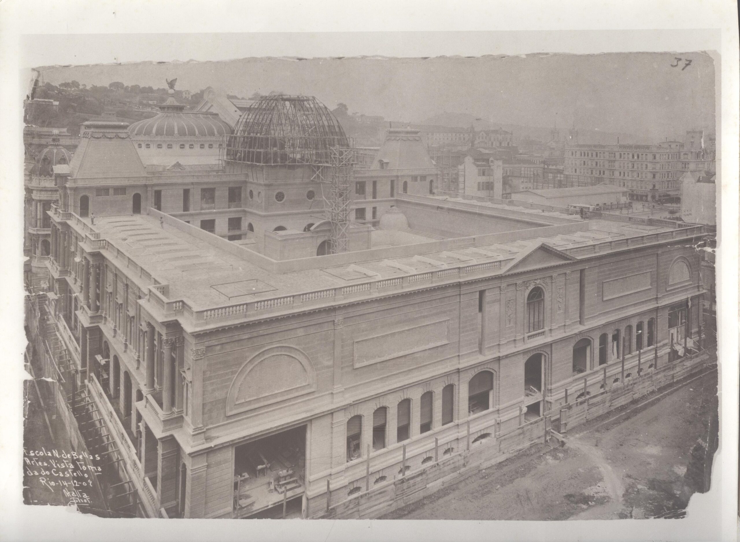 Fotografia antiga em tons de sépia, retratando a construção do museu, com destaque para a estrutura de cúpula parcialmente concluída no centro. Nota-se detalhes ornamentais e várias janelas distribuídas pela fachada. Há andaimes visíveis ao redor da cúpula e em outras partes do prédio, indicando que a obra ainda está em andamento.