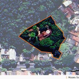 Imagem aérea do entorno urbano do Museu Solar Monjardim. No centro, uma área delimitada por linha laranja destaca o terreno do museu, com densa vegetação e o edifício histórico parcialmente visível entre as árvores. Ao redor, observa-se um bairro com ocupação consolidada. A imagem inclui a legenda com a identificação das edificações, no canto inferior direito, a escala gráfica e, na parte superior esquerda, uma seta indicando o ponto cardeal norte.